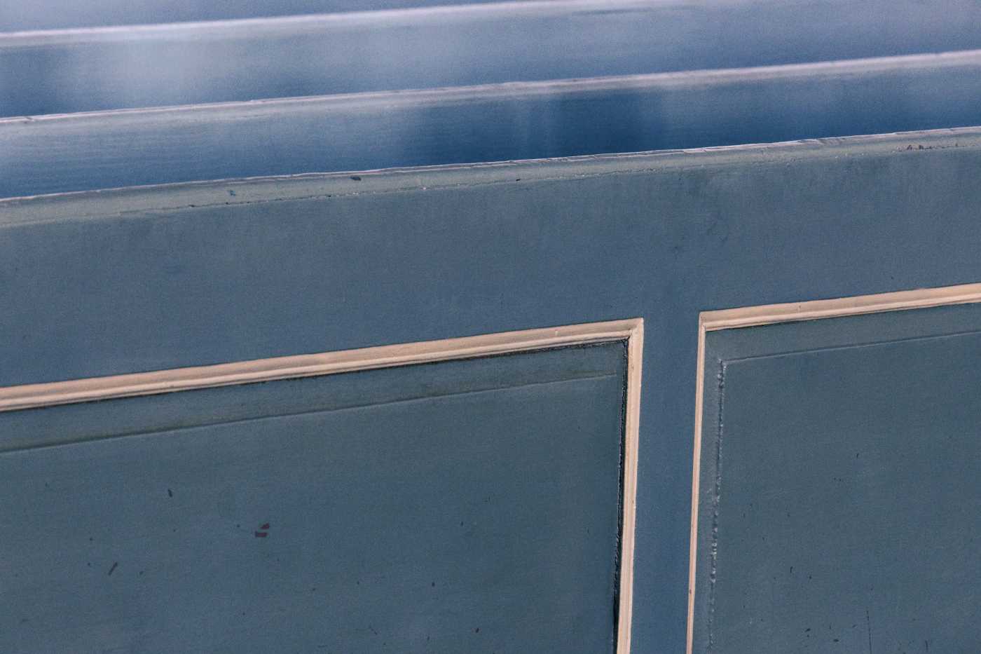 Blaue Kirchenbank mit weiß abgesetzten Rahmen, sehr nah und im Ausschnitt
