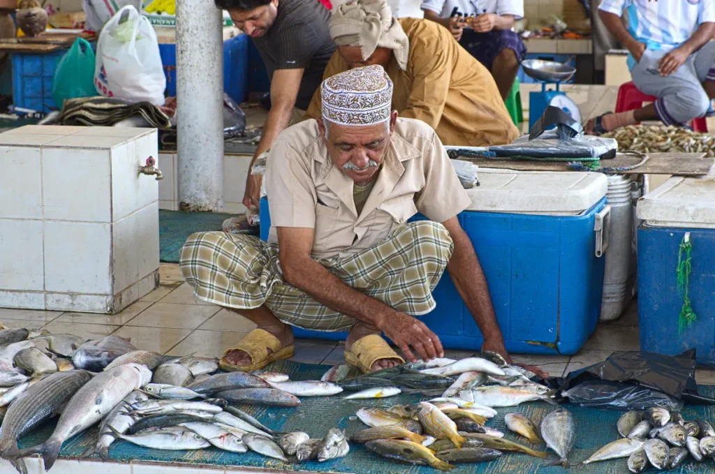 Mann sortiert Fische, die vor ihm auf einem Teppich liegen