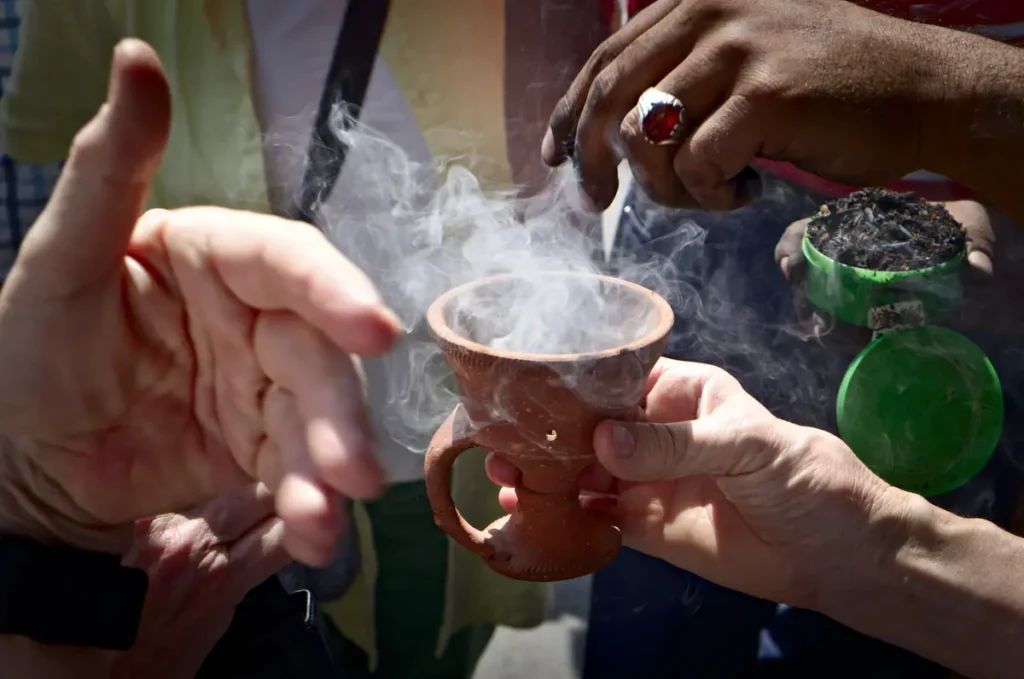 Hände um ein Weihrauchgefäß, weißer Rauch steigt daraus empor
